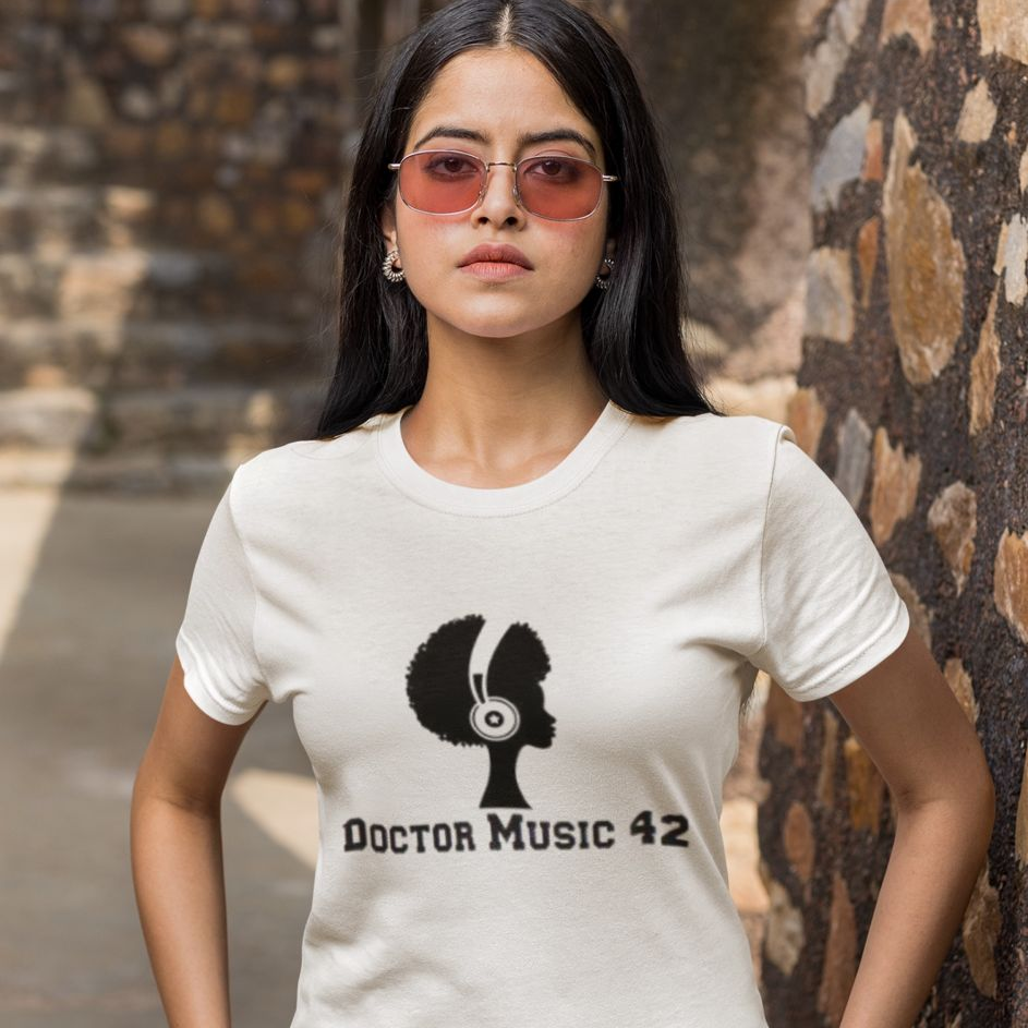 Woman wearing a white t-shirt with a graphic design and text, standing against a textured wall.